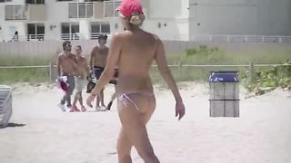 Женщина загорает в стрингах оголив сиськи на обыкновенном пляже